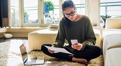 Een vrouw leest wat brieven en checkt daarbij haar telefoon
